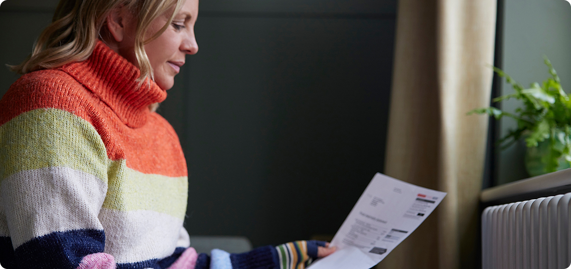 woman in winter jumper looking at a bill